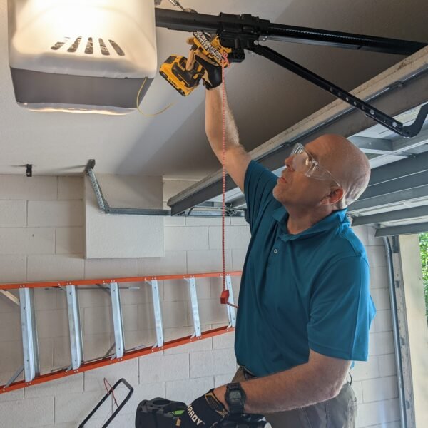Certified Garage Door Technician from Rocket Estate Builders servicing an older garage door opener in Central Florida.